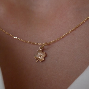 May include: A gold chain necklace with a four-leaf clover pendant.