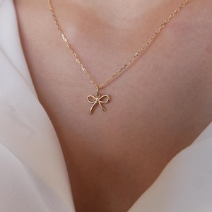 May include: A delicate gold necklace with a small bow pendant.