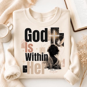 Puede incluir: Una sudadera de cuello redondo color crema con un estampado gráfico que incluye el texto God Is Within Her y Psalm 46:5. El diseño presenta la silueta de una persona, una paloma blanca, una cruz y formas geométricas abstractas en negro y beige.