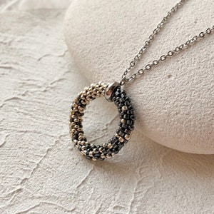May include: A silver chain necklace with a black and gold beaded circle pendant.