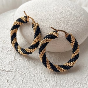 Aros con cuentas en zigzag en dorado y negro mate. Aros bohemios con cuentas retorcidas y atrevidas como regalo de cumpleaños para tu mejor amiga.