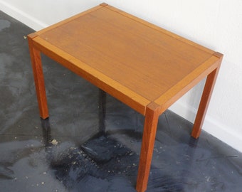 May include: A small, rectangular wooden side table with a light brown finish. The table has a simple design with four legs and a flat top.