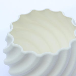 Close up image of a white 3D printed plant pot, photographed on a white background.