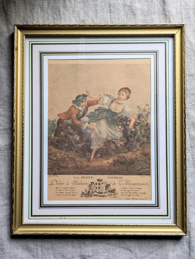 K&ouml;nnte beinhalten: Ein gerahmter Druck einer Vintage-Illustration, die ein Paar in einer Gartenlandschaft zeigt. Die Frau tr&auml;gt ein wei&szlig;es Kleid und der Mann eine braune Jacke und einen Hut. Der Druck ist mit "La Petite Therese Dedie a Madame de Blangermont" betitelt.