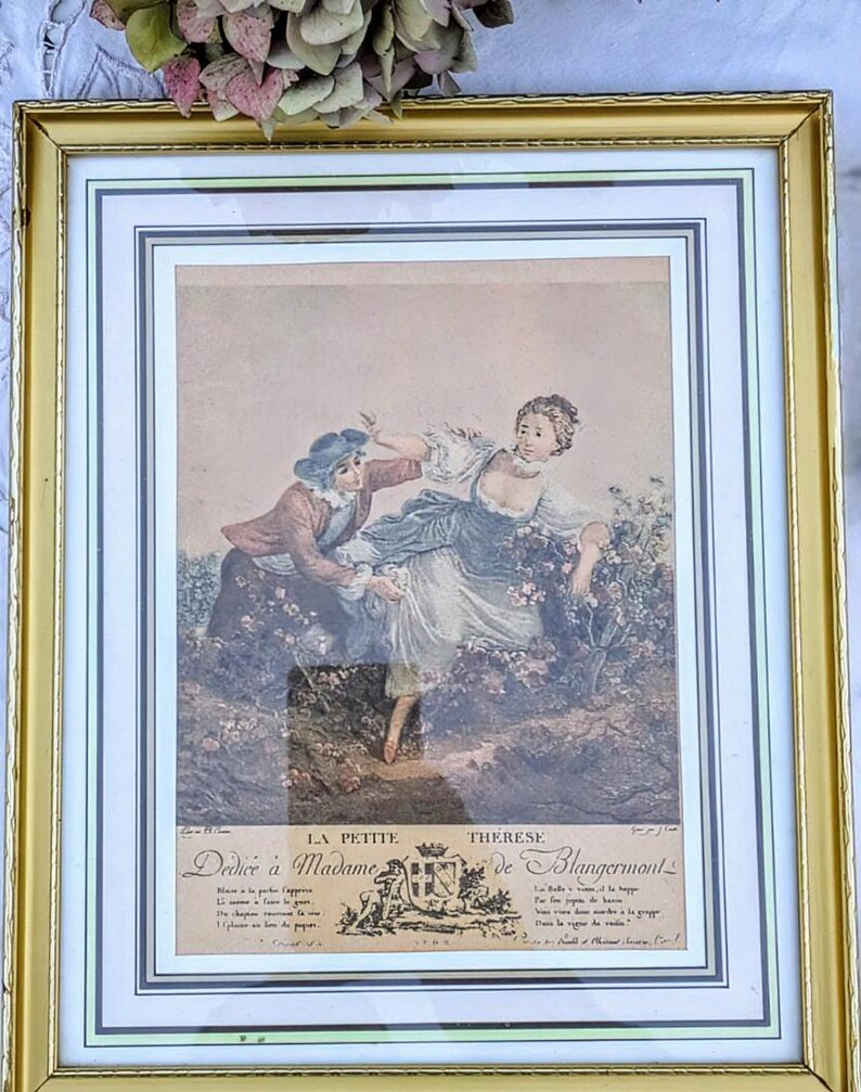 K&ouml;nnte beinhalten: Ein gerahmter Druck einer Vintage-Illustration, die eine Frau in einem wei&szlig;en Kleid und einen Mann in einer braunen Jacke zeigt. Die Frau h&auml;lt einen Blumenstrau&szlig; und der Mann streckt ihr die Hand entgegen. Der Druck ist mit "La Petite Therese Dediee a Madame de Blangormont" betitelt.