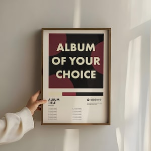 May include: A framed rectangular poster featuring a black background with dark red circular accents and the cream-colored text ALBUM OF YOUR CHOICE. Below, a tracklist section includes placeholders for song names, artist, and a Spotify code.