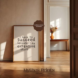 May include: A framed print with the text "I have to succeed because I like expensive stuff." The print is in a gold frame and is displayed in a room with hardwood floors. The words "multiple colours available!" are also visible.