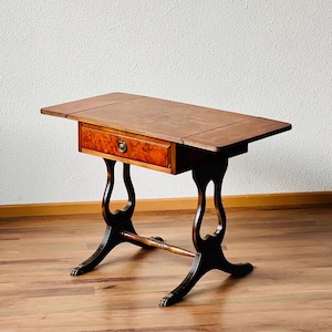 May include: A vintage wooden side table with a rectangular top and a single drawer. The table features a dark brown finish with ornate, curved legs and a decorative drawer pull. The table's dimensions are approximately 30 inches long, 18 inches wide, and 28 inches high.