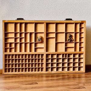 Op de afbeelding: Een houten lade-eenheid met meerdere vakken, perfect voor het organiseren van kleine items. De lade-eenheid is gemaakt van lichtbruin hout en heeft een eenvoudig, klassiek ontwerp.