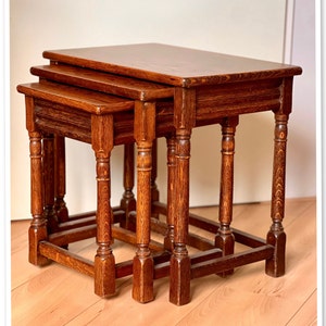 Puede incluir: Un conjunto de tres mesas nido de madera oscura con un diseño simple y tradicional. Las mesas son todas rectangulares y tienen patas torneadas.