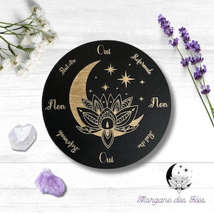 Peut inclure: Un plateau de divination circulaire en bois noir avec un croissant de lune doré, des étoiles et un motif de fleur de lotus. Le plateau porte les mots "Oui", "Peut être", "Non", "Reformule", "Oui", et "Peut être" écrits autour du bord.