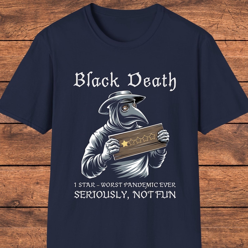 Op de afbeelding: Een marineblauw t-shirt met een afbeelding van een pestmeester met een hoed met brede rand en een vogelmasker. De arts houdt een houten bord vast met &eacute;&eacute;n gouden ster van de vijf. Tekst: Black Death, 1 STAR - WORST PANDEMIC EVER, SERIOUSLY, NOT FUN.