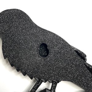 Puede incluir: Decoraci&oacute;n de pared con silueta de p&aacute;jaro de metal negro texturizado. El p&aacute;jaro tiene una superficie detallada y moteada y un ojal para colgar. El dise&ntilde;o presenta un p&aacute;jaro posado en una rama, adecuado para el hogar o el jard&iacute;n.