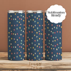 May include: Three stainless steel insulated tumblers with a festive design. The tumblers feature a navy blue background adorned with colorful string lights in shades of red, yellow, and green. The text "Sublimation Ready" is visible on one of the tumblers.