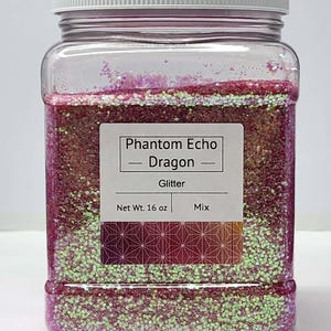 May include: A clear plastic jar filled with glitter. The label reads "Phantom Echo Dragon Glitter Mix, Net Wt. 454g." The glitter is a mix of pink, green, and gold colours, with a white lid.