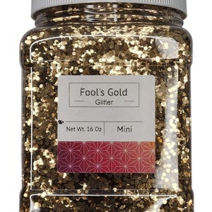 以下が含まれることがあります： 金色のグリッターが入った透明なプラスチックジャー。ラベルには「Fool's Gold Glitter」と「Net Wt. 454g Mini」と記載されています。グリッターは金色のトーンのミックスです。ジャーには白い蓋が付いています。