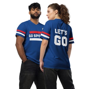 two people wearing a blue sports jersey. The man is facing front, displaying a design that says "Go Sports" with red and white stripes. The woman is facing backward displaying the design on the back which reads "Let's Go"