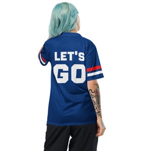 a blue haired person woman models the back of a blue sports fan jersey. The design simply says "Let's Go" with red and white stripes on the sleeves