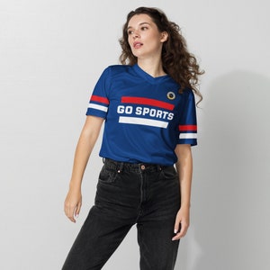 a young brunette woman models a blue fan jersey. The design says "Go Sports" with red and white stripes.