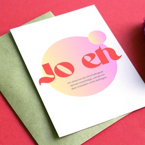 Könnte beinhalten: Eine weiße Karte mit einem rosa und gelben Kreis und dem Text "Jo en" in Rot. Der Text unter dem Kreis lautet "Ich erkenne die Sinnhaftigkeit deines Vorschlags, werde ihn aber trotzdem nicht befolgen."