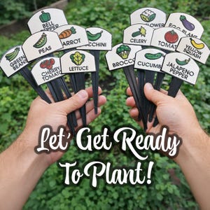 May include: Two hands holding sets of garden plant markers. Each marker has a black stake and a white label with a vegetable illustration and name, including bell pepper, peas, carrot, courgette, and tomato. The text "Let's Get Ready To Plant!" is at the bottom.