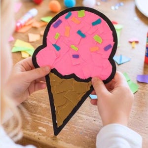 Puede incluir: Un recorte de papel en forma de cono de helado con una bola rosa cubierta de peque&ntilde;os trozos de papel multicolor y una base de cono marr&oacute;n. Toda la forma est&aacute; delineada con un borde negro grueso, creando una apariencia de estilo collage.