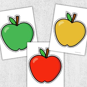 May include: Three apple-shaped cutouts in green, yellow, and red, each with a brown stem and green leaf. The apples have a black outline with a dashed border, set against a white background.