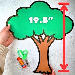 Pode incluir: Recorte de árvore verde com tronco castanho e contorno preto, medindo 49,5 cm de altura. A árvore é segurada por mãos, com tesoura e cola em bastão visíveis abaixo. A árvore é um material de artesanato.