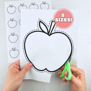 May include: White paper with apple outlines and the text "5 SIZES!" is being cut with green scissors. Additional apple outlines are visible on a separate sheet of paper. The apple outlines have a black border and a dotted cutting line.