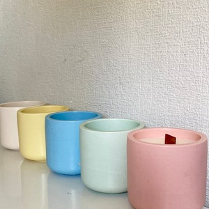 Peut inclure: Rangée de six bougies cylindriques aux couleurs pastel : blanc, jaune, bleu, vert menthe et rose. Chaque bougie a une finition lisse et mate et une mèche en bois.