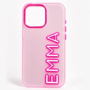 May include: A translucent light pink phone case featuring a vibrant hot pink camera cutout border and the name EMMA embossed vertically in bold, white, hot pink-outlined capital letters along the right side of the protective cover.