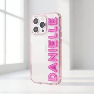 Peut inclure: Coque de téléphone transparente avec bordure rose et le nom "DANIELLE" en lettres bulles roses. Conçue pour un smartphone avec plusieurs objectifs.