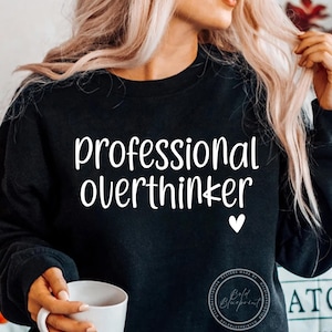 May include: Black sweatshirt with the text "professional overthinker" in white lettering and a small white heart.