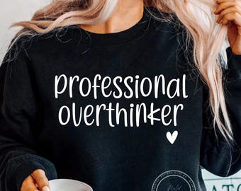 May include: Black sweatshirt with the text "professional overthinker" in white lettering and a small white heart.