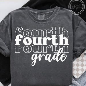 May include: Dark gray crew neck t-shirt with the words "fourth fourth fourth grade" in white, stacked vertically. The shirt has a vintage, washed look and a relaxed fit. A phone with a checkered case is visible.