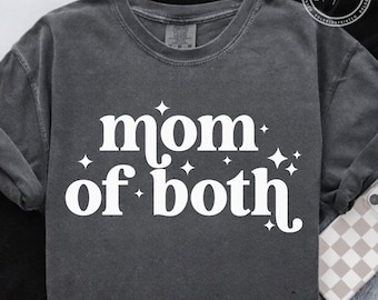 Op de afbeelding: Donkergrijze longsleeve met de witte tekst "mom of both", versierd met sterren. De shirt heeft een ronde hals en een relaxte pasvorm. Een telefoon met een geruit hoesje is zichtbaar.