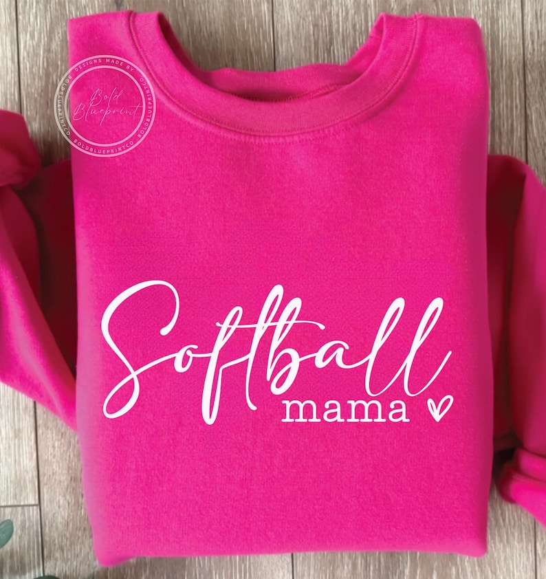 May include: A pink sweatshirt with the text "Softball mama" in white cursive lettering with a small heart.