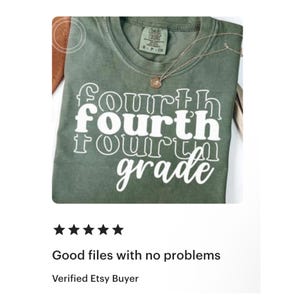 May include: A green t-shirt with the words "Fourth Grade" in a stacked, white font. The shirt has a crew neck and a small tag at the neckline. A gold necklace with a pendant is draped on the shirt.