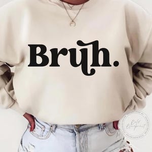 May include: A cream coloured sweatshirt with the word "Bruh." printed in black.