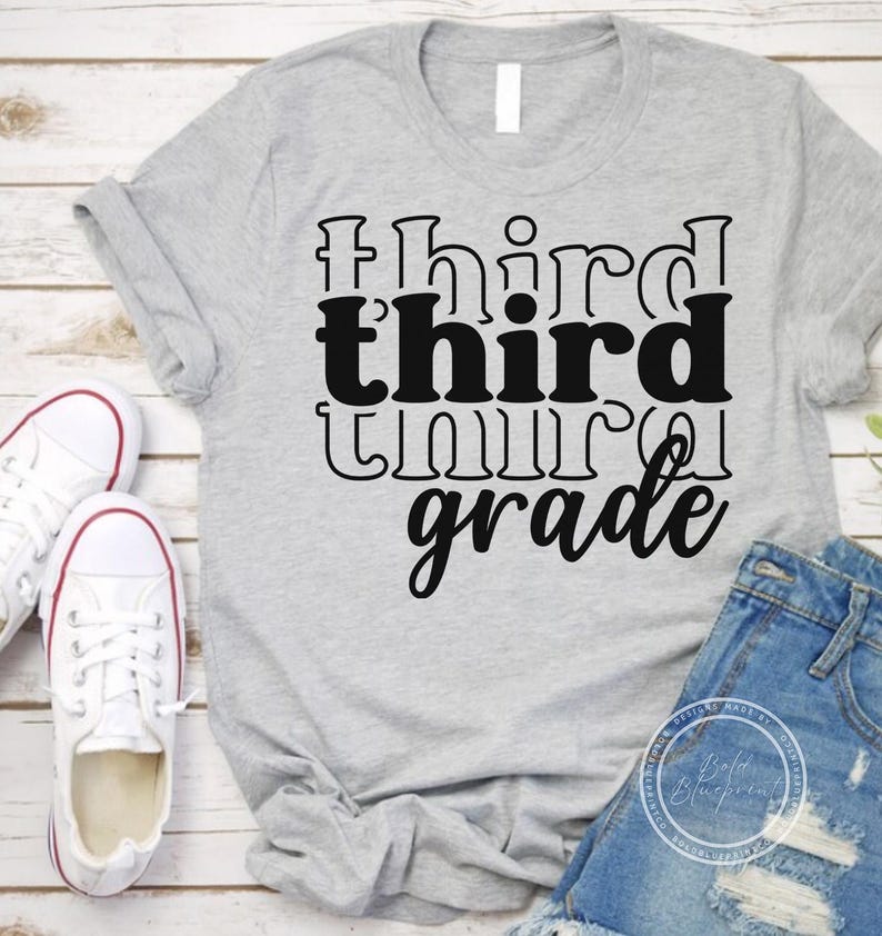 May include: A light gray t-shirt with the words "third grade" in a black, bold font. The shirt is paired with denim shorts and white sneakers with red trim. The shirt is likely for a student.