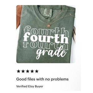May include: A green t-shirt with the words "fourth grade" in a stacked, white font. The shirt has a crew neck and a small tag at the neckline. A gold necklace with a pendant is draped over the shirt.
