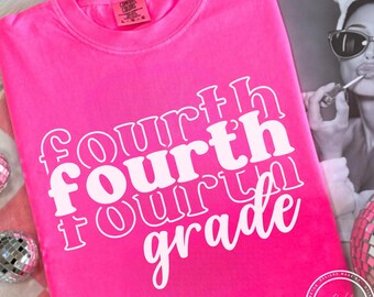 Puede incluir: Camiseta rosa brillante con las palabras "Fourth Grade" en una fuente retro blanca apilada. La camiseta está hecha de un material suave. La camiseta es de la marca Comfort Colors.