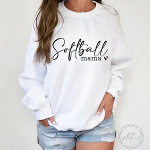 May include: White sweatshirt with the text "Softball mama" in black script with a small heart.