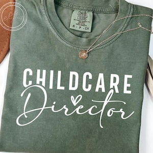 May include: A green t-shirt with the text "CHILDCARE Director" in white lettering. A small white heart is next to the word "Director".
