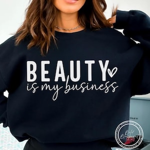 May include: Black sweatshirt with the text "BEAUTY is my business" in white block and script lettering, with a heart symbol. The sweatshirt is a crew neck style.