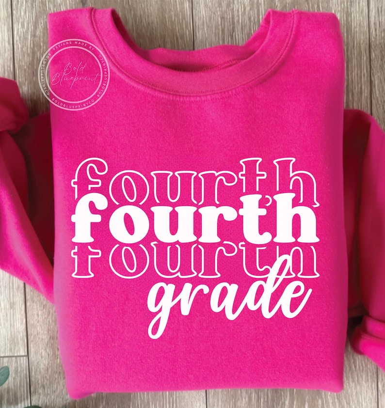 May include: A bright pink sweatshirt with the words "Fourth Grade" in white, stacked vertically. The sweatshirt has a crew neck and long sleeves. The text is in a bold, playful font.