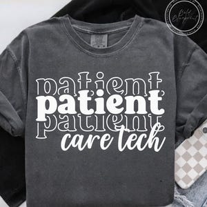 Może przedstawiać: Ciemnoszara bluza z okrągłym dekoltem z białym napisem "patient patient patient care tech", ułożonym pionowo. Bluza ma wygląd vintage. Widoczny jest telefon z etui w kratkę.