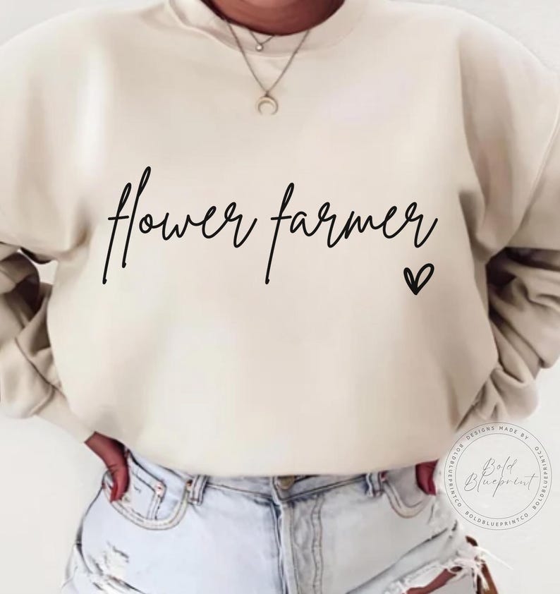 May include: A cream colored sweatshirt with the text "flower farmer" in black script with a small heart symbol.