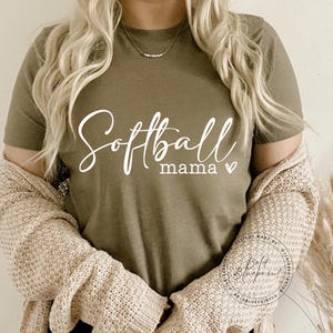 May include: A green t-shirt with the text "Softball mama" in white cursive lettering with a small heart symbol.