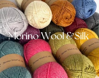 Puede incluir: Una colección de ovillos de lana en varios colores, incluyendo verde azulado, rosa, amarillo, naranja y gris. La lana está etiquetada como "Merino Wool & Silk".